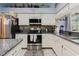 Galley kitchen with stainless steel appliances, white cabinets, granite countertops, and decorative items on display at 11209 Pocket Brook Dr, Tampa, FL 33635