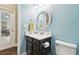 Bathroom with blue walls, black cabinets, white sink, round mirror and door leading outside at 11852 Lake Lucaya Dr, Riverview, FL 33579