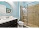 Bathroom with tan tiled shower, blue walls, black cabinets, and a round mirror above a white sink at 11852 Lake Lucaya Dr, Riverview, FL 33579