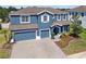 Charming two-story blue home with a two-car garage, a paver driveway, and manicured landscaping at 11852 Lake Lucaya Dr, Riverview, FL 33579