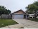 Single-story home featuring a gray exterior, stone accents, driveway, and fenced yard at 12312 Golden Oak Cir, Hudson, FL 34669