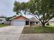 Charming single-story home with a gray exterior, stone accents, and a large tree in the front yard at 12312 Golden Oak Cir, Hudson, FL 34669