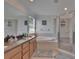 Bathroom featuring double sinks, soaking tub, and walk-in shower with neutral wall-to-wall tile at 13421 Sydney Rd, Valrico, FL 33594
