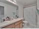 Bright bathroom featuring a double sink vanity and a shower with patterned curtain at 13421 Sydney Rd, Valrico, FL 33594