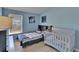 bedroom with blue walls, window, twin bed, and a crib, illuminated by natural light at 13421 Sydney Rd, Valrico, FL 33594