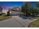 Charming two-story home with a spacious driveway and a three-car garage, surrounded by mature trees under a dusk sky at 13421 Sydney Rd, Valrico, FL 33594