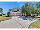 Charming two-story home with a spacious driveway and a three-car garage, surrounded by mature trees under a sunny sky at 13421 Sydney Rd, Valrico, FL 33594
