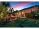 The backyard at dusk has a firepit, paver patio, and well-manicured landscaping at 15608 Starling Water Dr, Lithia, FL 33547