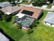 Aerial view of a property showcasing a screened pool, well-maintained lawn, and solar panels at 1575 Wicklow Dr, Palm Harbor, FL 34684