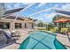 Relaxing pool and patio area featuring sun loungers, lush landscaping, and solar panels at 1575 Wicklow Dr, Palm Harbor, FL 34684