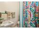 A bathroom area with a decorated colorful shower curtain, and a sink with light-green trim at 16044 Stur St, Brooksville, FL 34604