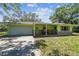 A charming single-story home showcases a colorful green exterior, a garage, and a welcoming front porch at 16044 Stur St, Brooksville, FL 34604