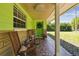 Inviting covered porch features two rocking chairs with decorative pillows placed in front of a brightly-colored green door at 16044 Stur St, Brooksville, FL 34604