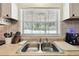 A kitchen sink and countertop by a window overlooking trees, with updated tile and nice lighting at 16044 Stur St, Brooksville, FL 34604