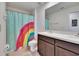 Bright bathroom featuring a dual sink vanity and a fun rainbow shower curtain at 16894 Delia St, Wimauma, FL 33598