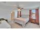 Comfortable bedroom with a ceiling fan, neutral carpet, and bright windows with pink curtains at 16894 Delia St, Wimauma, FL 33598
