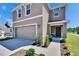 Two story home features a two car garage, neutral stucco facade, manicured lawn, and covered front porch at 16894 Delia St, Wimauma, FL 33598