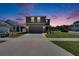 Two story home featuring a two car garage and manicured lawn at dusk at 16894 Delia St, Wimauma, FL 33598