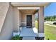 Covered front porch features a black front door, modern exterior lighting, and neutral stucco columns at 16894 Delia St, Wimauma, FL 33598