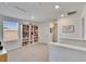 Bright hallway with soft carpet, a bookcase with sunny window and door leading to rooms at 16894 Delia St, Wimauma, FL 33598