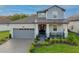 Charming two-story home featuring a covered porch, gray brick driveway, and a manicured lawn at 19475 Bristol Wood Pl, Brooksville, FL 34601