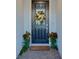 Stylish front door adorned with a festive wreath, flanked by potted plants, and brick entryway at 19475 Bristol Wood Pl, Brooksville, FL 34601