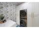 Modern laundry room with stacked washer/dryer, white cabinets, and wallpaper at 19475 Bristol Wood Pl, Brooksville, FL 34601