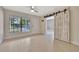 Sunlit living room showcases a decorative barn door and wood-look tile floors, enhancing the home's modern charm at 2106 W Saint Isabel St, Tampa, FL 33607