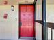 Bright red front door with modern hardware, doorbell, and wall-mounted light fixture at 2693 Sabal Springs Cir # 206, Clearwater, FL 33761