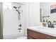 Clean bathroom with white tile, shower-tub combo, modern fixtures, and a wood vanity for a functional design at 28680 Cozy Creek Dr, Wesley Chapel, FL 33543