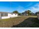 Backyard shot with a grassy lawn and concrete slab, partially fenced, backing up to neighboring houses at 3706 Cambridge St, New Port Richey, FL 34652