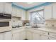 Efficient kitchen with a stainless steel sink, white cabinetry, and natural lighting, ideal for cooking at 3706 Cambridge St, New Port Richey, FL 34652