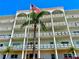 Exterior view of a multistory building showcasing balconies and a palm tree beneath an American flag at 5501 80Th N St # 509, St Petersburg, FL 33709