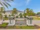 The community entrance sign is surrounded by palm trees, lush green landscaping, and the community homes in the background at 5710 Grand Sonata Ave, Lutz, FL 33558