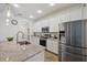 Modern kitchen featuring white cabinets, stainless steel appliances, a speckled countertop, and stylish pendant lights at 5710 Grand Sonata Ave, Lutz, FL 33558