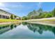 Wide angle of a pond surrounded by community townhomes and a white fence, reflecting the sky for a serene view at 5710 Grand Sonata Ave, Lutz, FL 33558