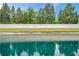 Scenic view of the pond, accented by a white fence and lush greenery, offering a peaceful backyard retreat at 5710 Grand Sonata Ave, Lutz, FL 33558