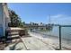 Backyard with brick steps leading to a sandy area by the water and private dock at 712 Sunset Cv, Madeira Beach, FL 33708