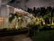 Elegant home exterior illuminated at night, featuring palm trees and lush greenery for a tropical feel at 712 Sunset Cv, Madeira Beach, FL 33708