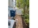Exterior with brick pathway, white fence, and trash receptacles, bordered by lush, tropical plants at 712 Sunset Cv, Madeira Beach, FL 33708