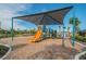 Community playground offering a colorful slide and play structures set on a mulch ground under a shade canopy at 7139 Steer Blade Dr, Zephyrhills, FL 33541