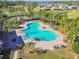 Community pool offers a unique shape and ample space for relaxation, surrounded by lounge chairs and palm trees at 7139 Steer Blade Dr, Zephyrhills, FL 33541