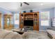 Spacious living room featuring wood-look floors, windows with blinds, and display cabinetry at 8604 Vicksburg Rd, Spring Hill, FL 34608