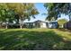 Spacious backyard with mature trees, lush lawn, and a charming single-story home in a serene setting at 10137 Oleander Dr, Port Richey, FL 34668