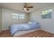 Comfortable bedroom features wood-look floors, a ceiling fan, and dual windows at 10137 Oleander Dr, Port Richey, FL 34668