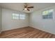 This bedroom features wood floors, ceiling fan, two windows and neutral paint at 10137 Oleander Dr, Port Richey, FL 34668