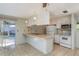 Bright kitchen with white cabinets, tile backsplash, stainless steel appliances, and view to Florida Room at 10137 Oleander Dr, Port Richey, FL 34668
