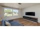 Bright living room with hardwood floors, large window, sleek TV console, and comfortable sofa at 10137 Oleander Dr, Port Richey, FL 34668