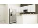 Bright kitchen featuring white cabinetry, stainless steel refrigerator, and granite countertops at 10240 Trumpet Honeysuckle Way, San Antonio, FL 33576