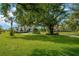Beautifully landscaped front yard featuring lush green grass and mature trees creating a park-like setting at 10509 Broadland Pass, Thonotosassa, FL 33592